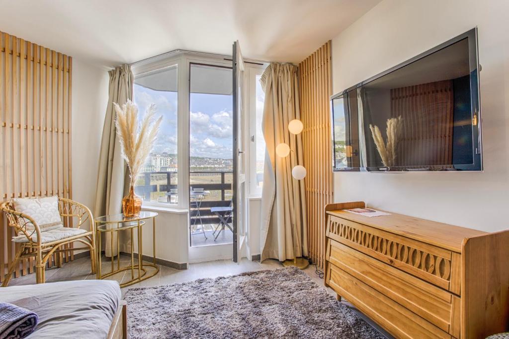 a bedroom with a bed and a television and a table at LA REV'RIE - vue sur mer avec balcon in Deauville