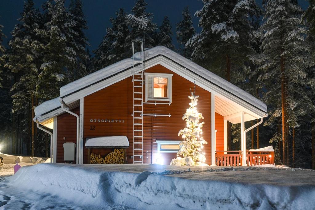 a cabin with a christmas tree in front of it at OtsoPirtti: Maria and Otso Apartments in Kolinkylä