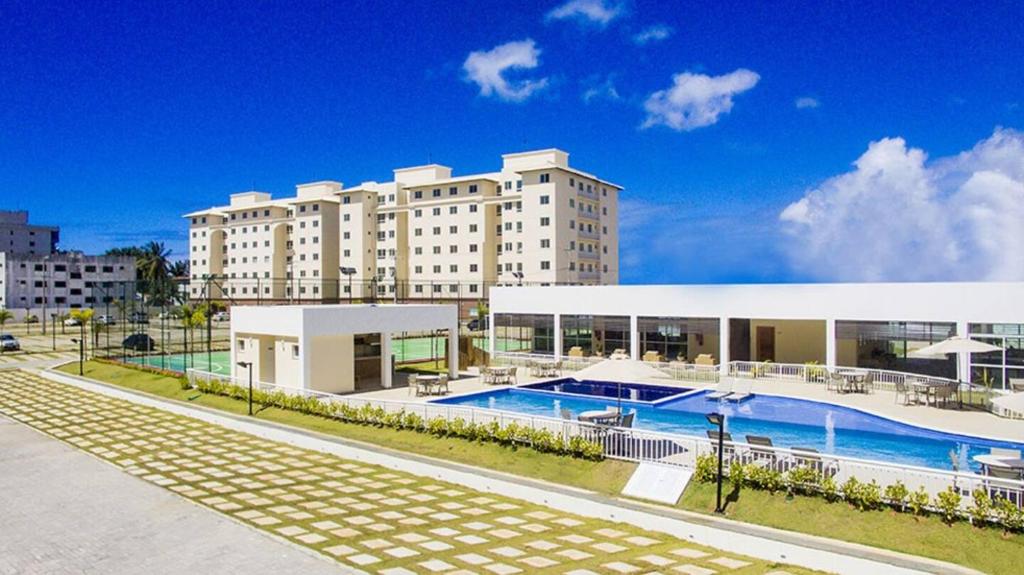 a large building with a swimming pool in front of it at Apartamento em Ilhéus próximo as Praias in Ilhéus