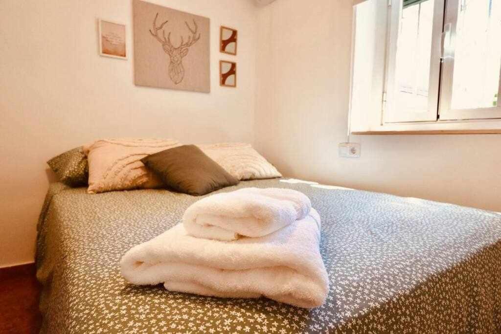 Una cama con un montón de toallas blancas. en Fantastico apartamento en Granada, en Granada