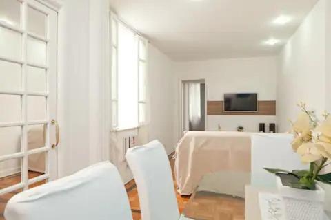 a living room with two white chairs and a table at Apartamento Epitácio Pessoa in Rio de Janeiro