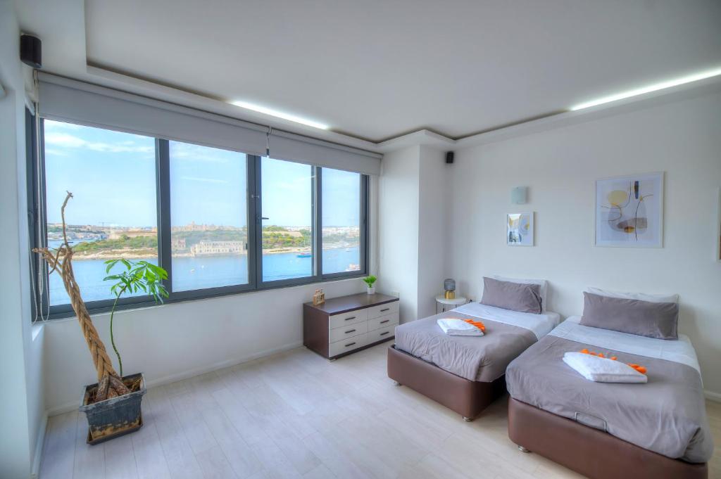 1 dormitorio con 2 camas y ventanas grandes en Bright and spacious 3 bedroom apartment with breathtaking views - GOSLM5, en Sliema
