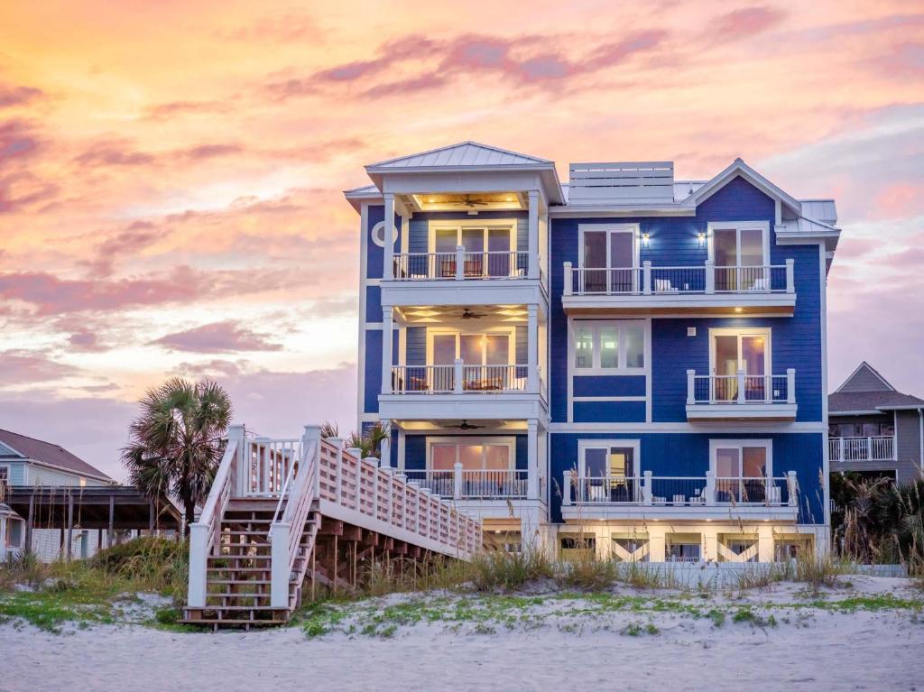 a blue house on the beach at sunset at Huge Beachfront Home with Pool, Hot Tub, Elevator- 4 night minimum stay in Myrtle Beach