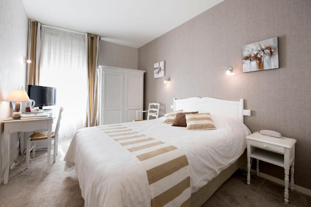 a bedroom with a large white bed and a desk at Hotel Biney in Rodez
