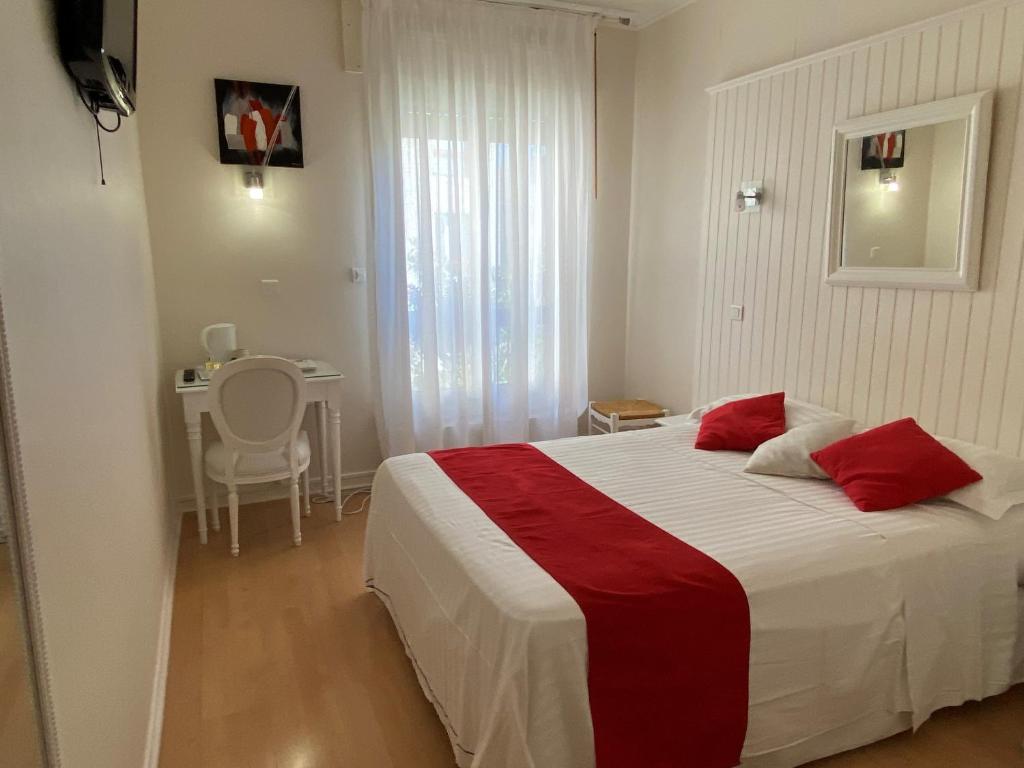 a bedroom with a bed with red pillows and a table at Hotel Biney in Rodez