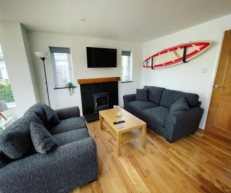 a living room with two couches and a surfboard on the wall at Mary Cottage, Braunton, Devon in Braunton