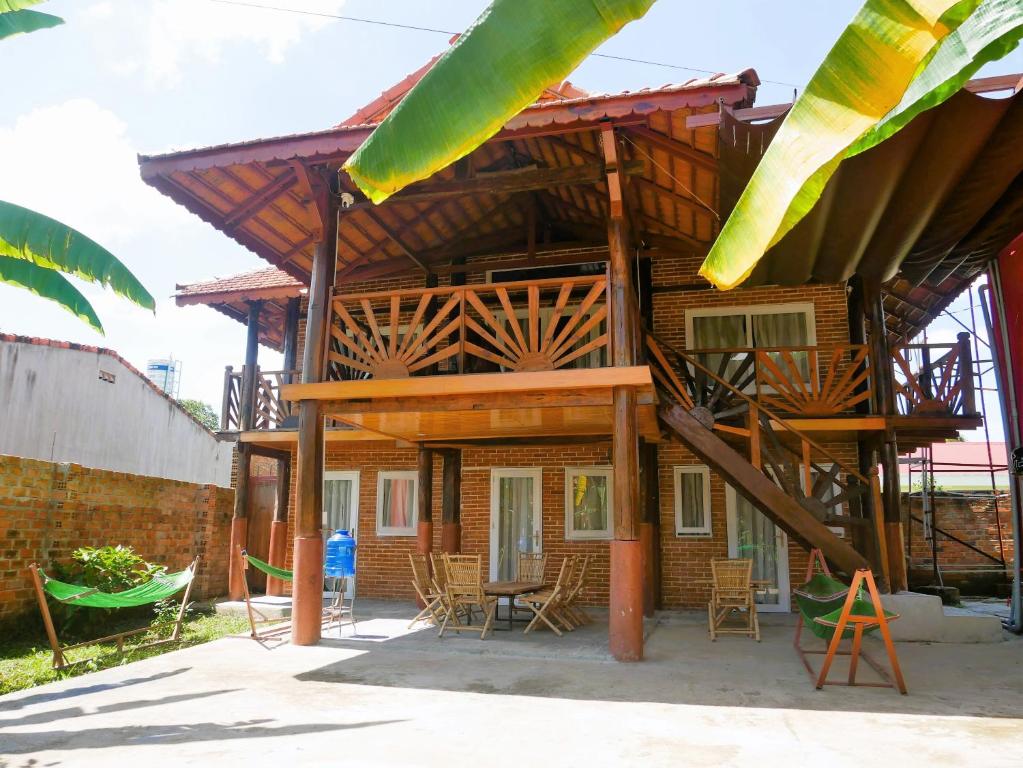 a house with a wooden roof with chairs and tables at Xô Xôn Homestay in Kon Rơbang