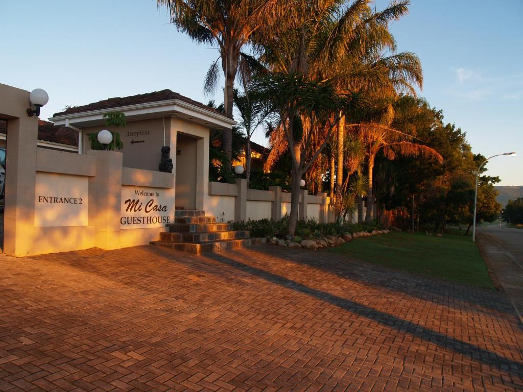 a building with palm trees and a brick driveway at Mi Casa Guest House in Uitenhage
