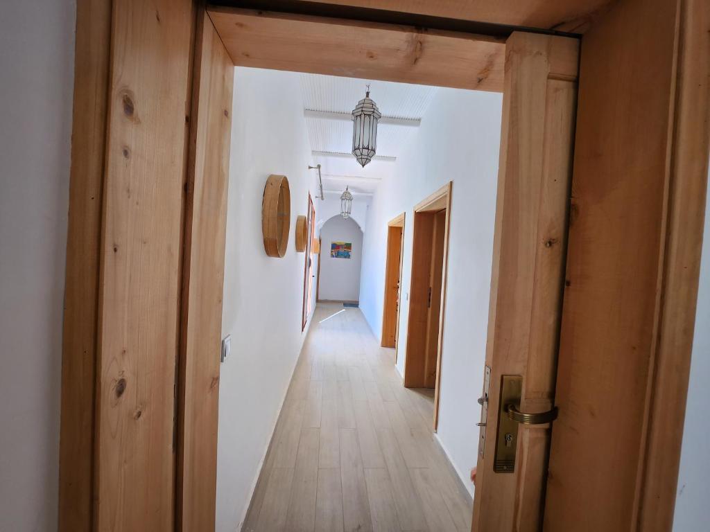 a hallway with white walls and a wooden door at AdaZen Ecolodge in Azilal