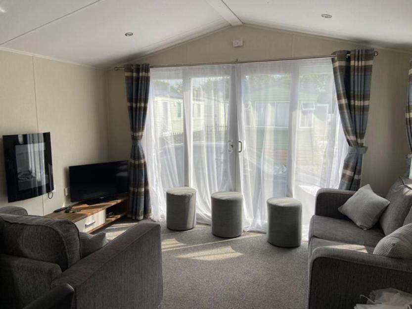 a living room with two couches and a tv and curtains at Adams Caravan Holidays in Morecambe