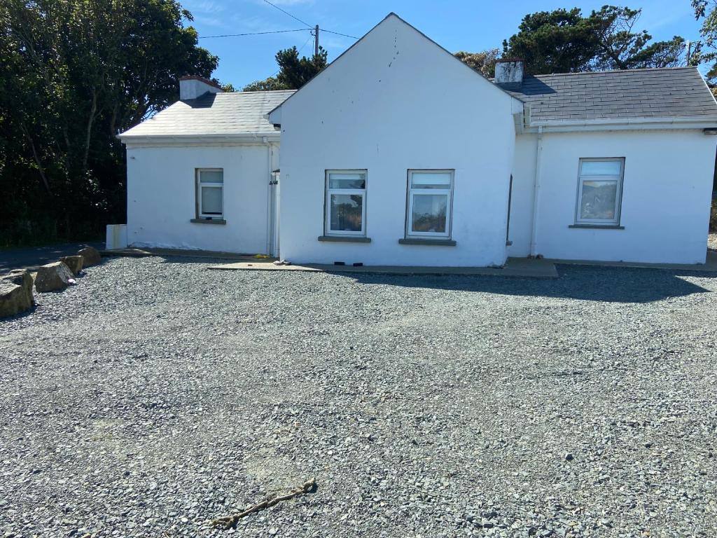 a white house with a gravel driveway at Tranquil 2 Bedroom Cottage With Hot Tub Sea View Teach Cha in Sessiagh