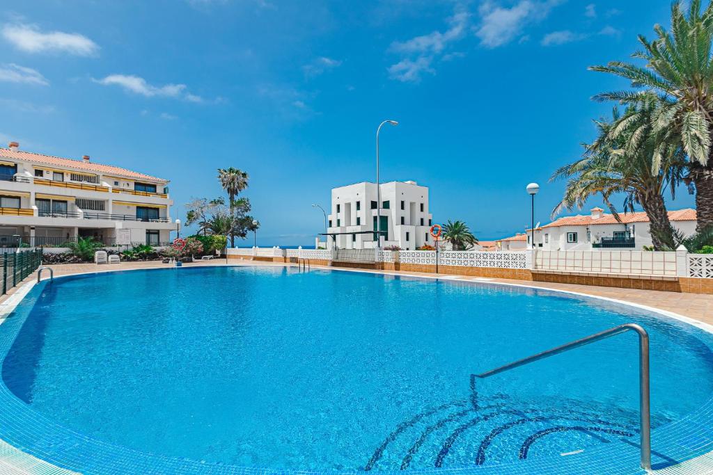 duży niebieski basen z budynkiem w tle w obiekcie BuenaVista Sunflower Apartment in Playa La Arena w mieście Puerto de Santiago