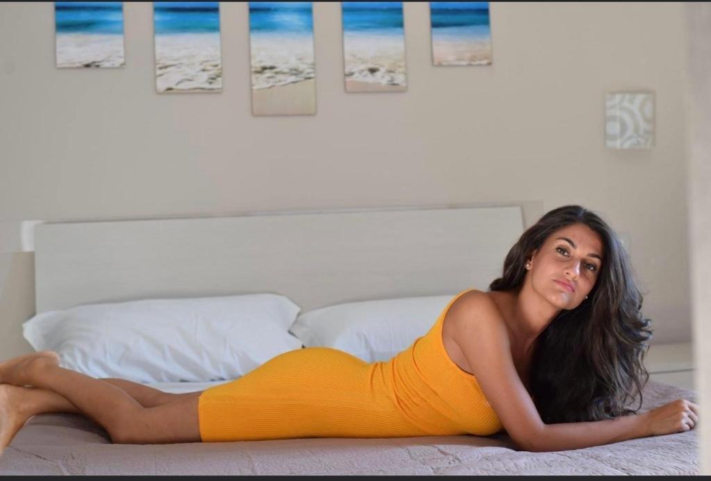 a woman in an orange dress laying on a bed at Lvresidence Roccelletta in Catanzaro Lido