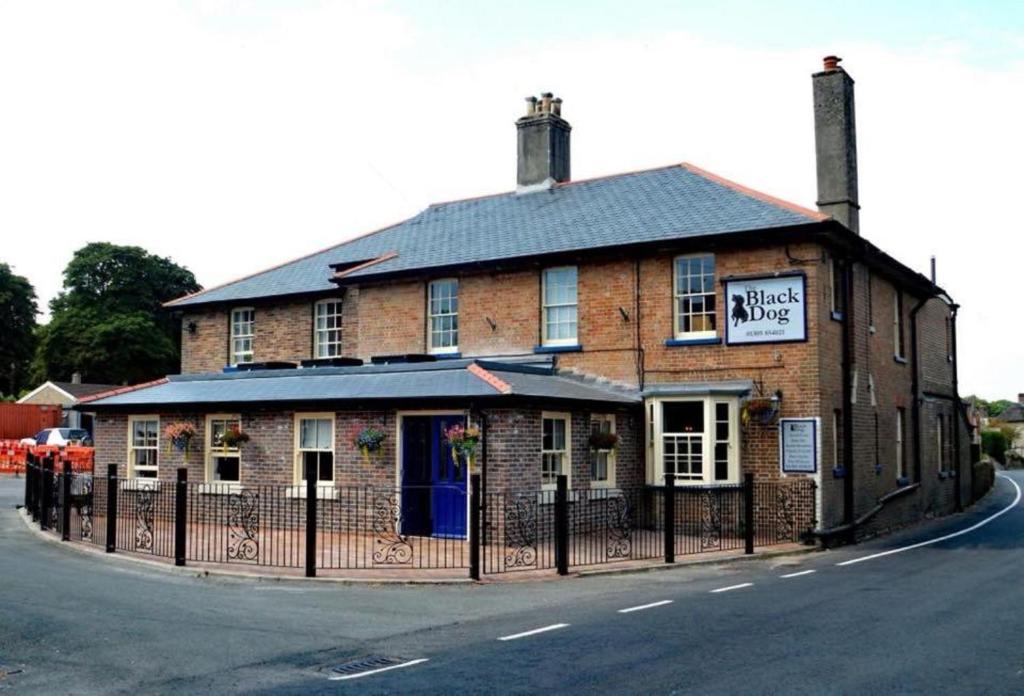 um edifício de tijolos ao lado de uma rua em The Black Dog Inn em Broadmayne