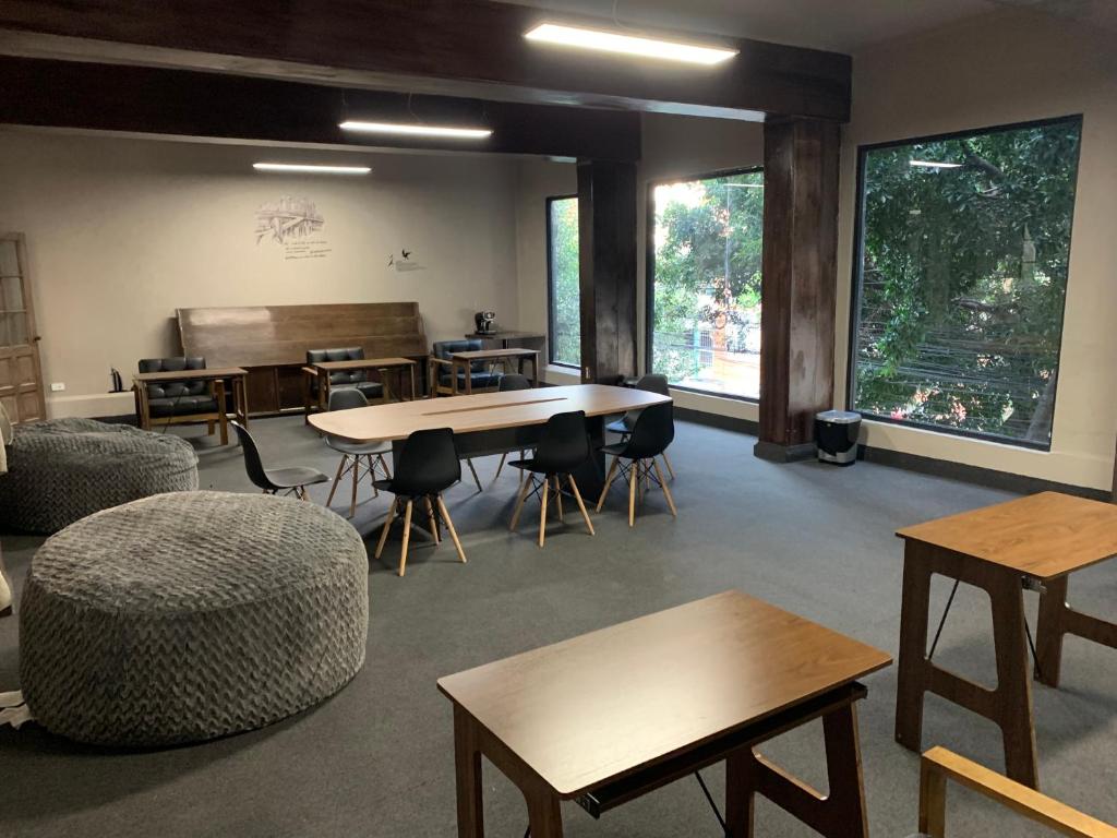 a large room with tables and chairs and windows at FRONTERA 49 Roma Norte Hostal in Mexico City