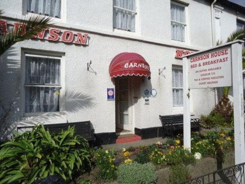 a white building with a red awning and a restaurant at Carnson House in Penzance