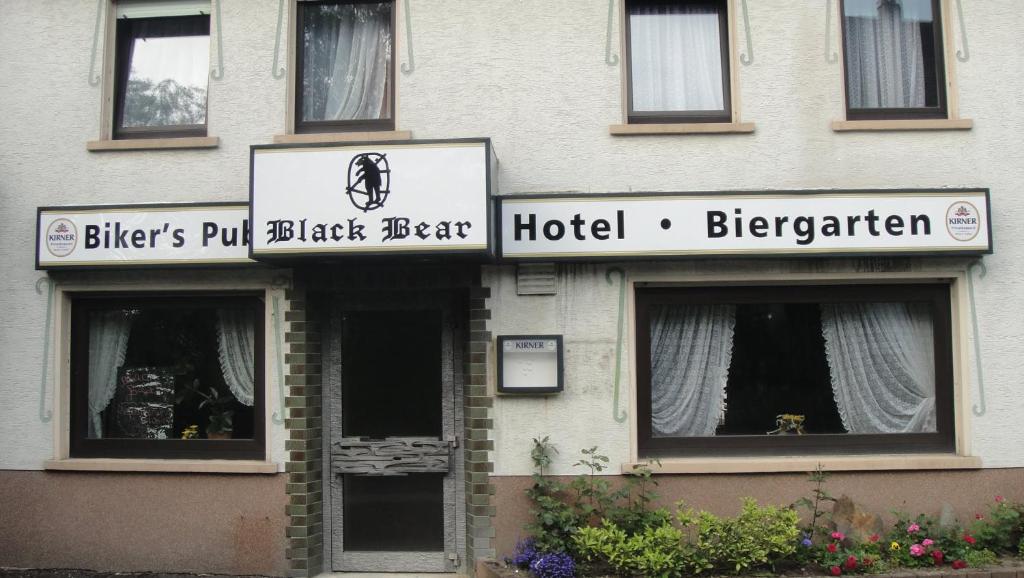 a white building with a sign for a hotel at Black Bear Bikers Pub-Hotel in Kempfeld