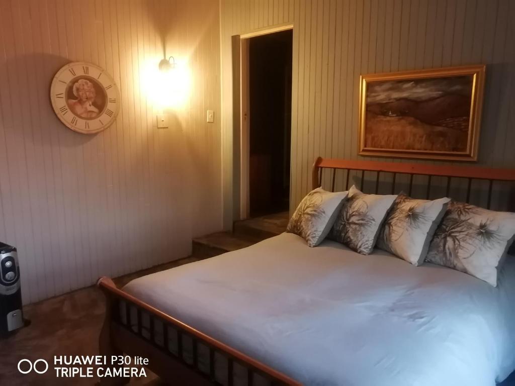 una camera da letto con un letto con lenzuola bianche e un orologio a muro di The Marilyn Room a Centurion