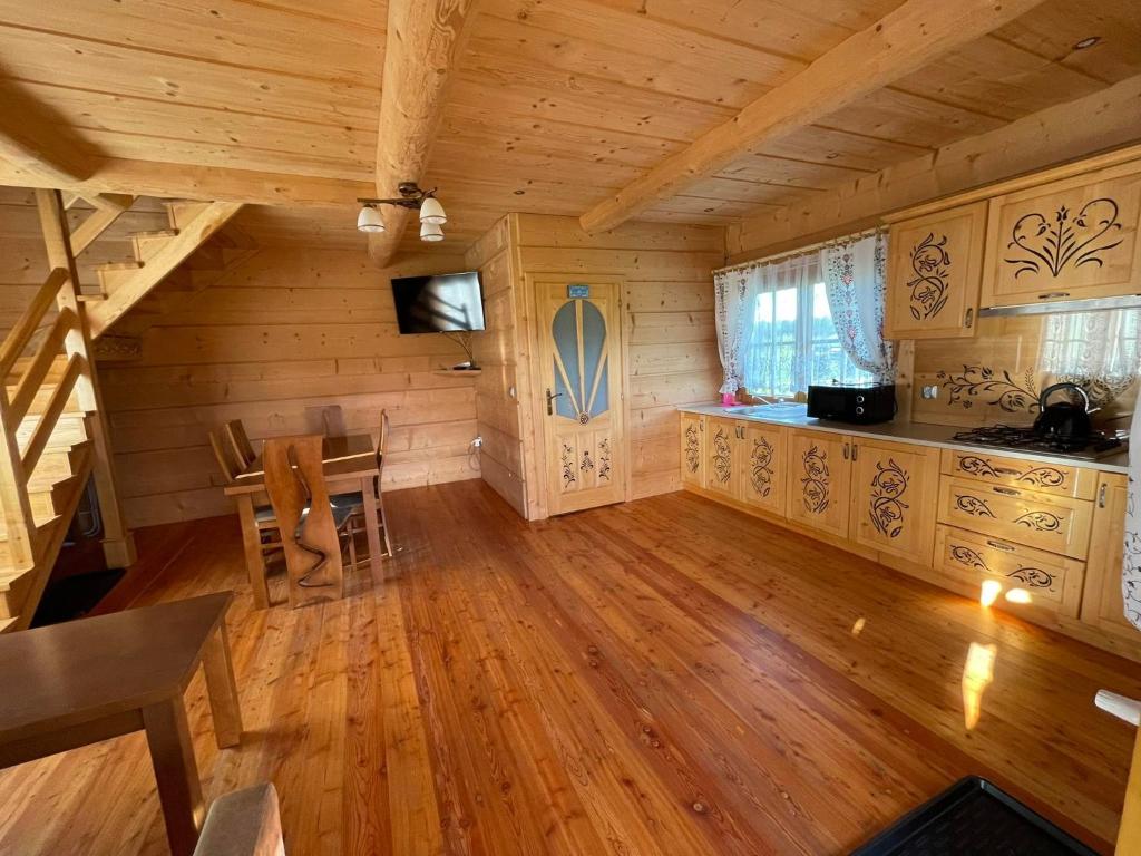 Habitación grande con cocina y escalera en una cabaña de madera. en Domek u Orszulaków en Witów