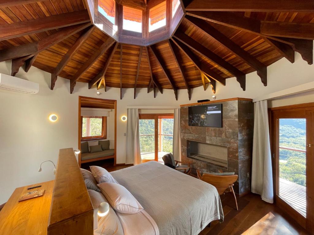 ein Schlafzimmer mit einem großen Bett und einem Kamin in der Unterkunft Atiaia Jungle River Retreat in Visconde De Maua
