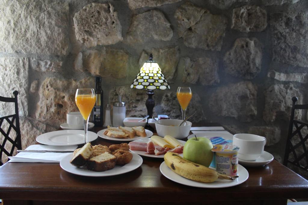 Hotel Rural San Pelayo في San Pelayo: طاولة مع أطباق من الطعام وكؤوس من عصير البرتقال