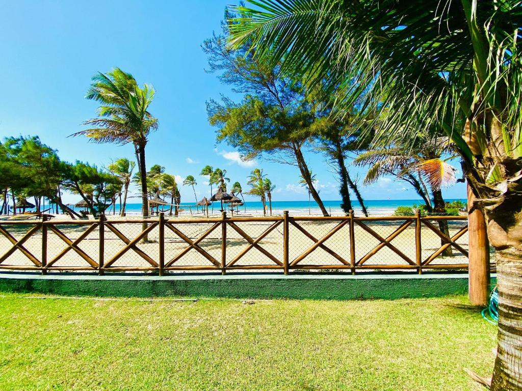 una valla frente a una playa con palmeras en Resort VG SUN por Be My Guest! en Caucaia