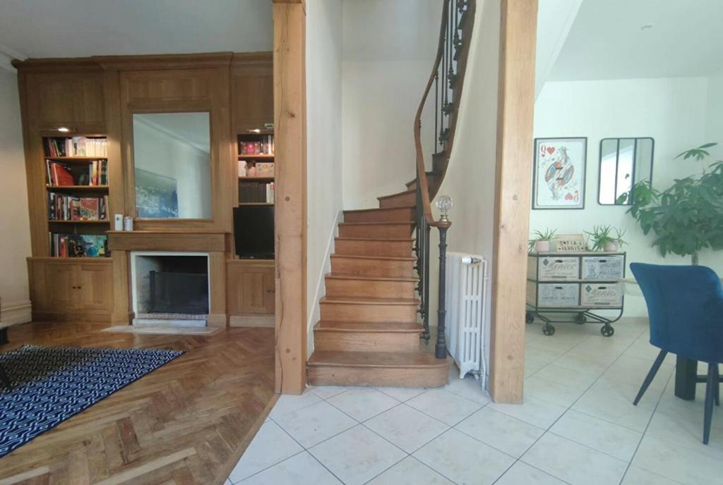 a living room with a staircase in a house at Maison de maître, un coin de verdure en hyper centre in Lisieux