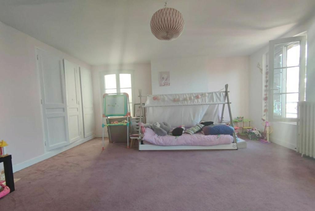 a room with a bed with two people laying on it at Maison de maître, un coin de verdure en hyper centre in Lisieux