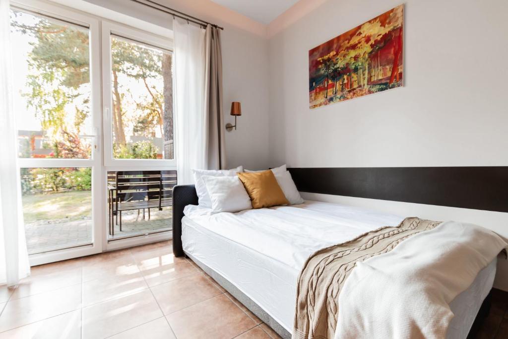 a bedroom with a bed and a large window at Pokoje przy Plaży Dźwirzyno -Pelikan Resort in Dźwirzyno