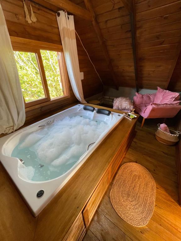 a large bath tub in a room with a window at Chalé de Pedra Recanto Verde dos Canyons in Praia Grande