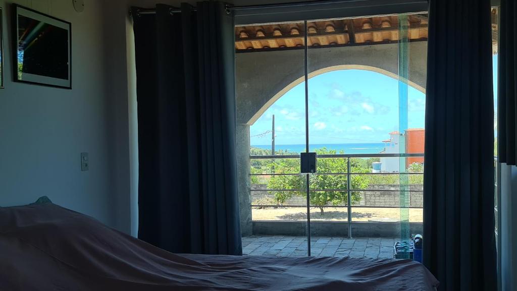 ein Schlafzimmer mit einem Fenster mit Blick auf das Meer in der Unterkunft Tabatinga Relax Apartamentos in Conde