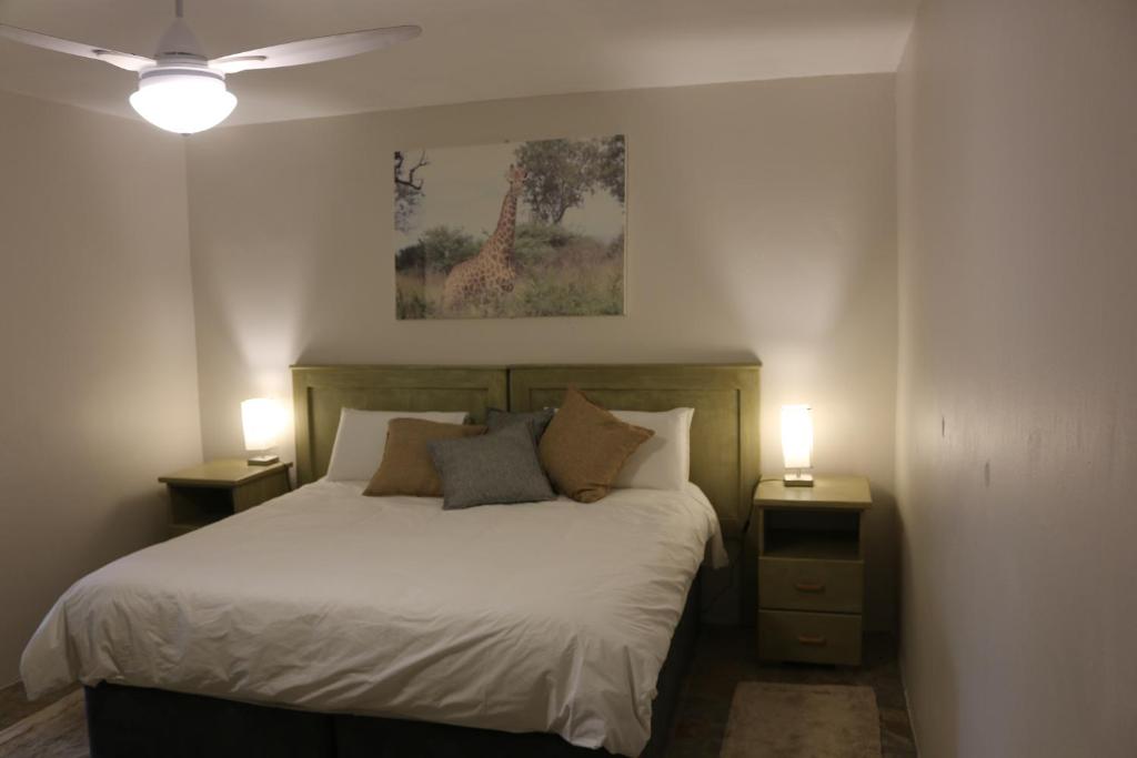 1 dormitorio con 1 cama con 2 mesitas de noche y 2 lámparas en Livivane Guest House en Simunye