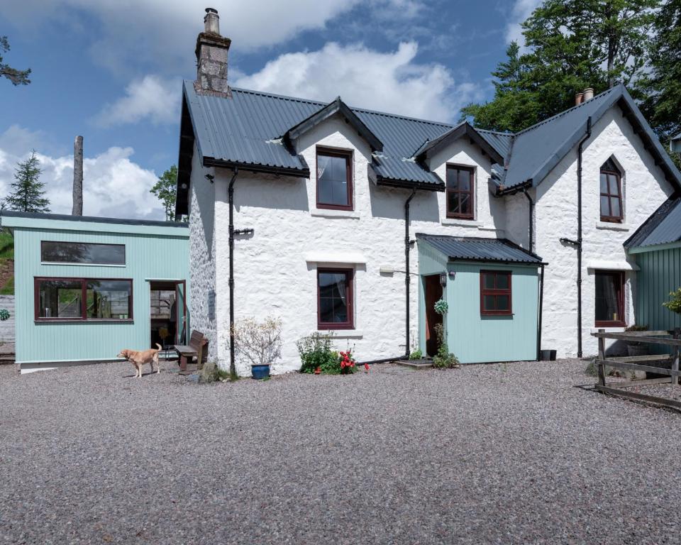 a white house with a dog in front of it at Gulabin Lodge in Glenshee