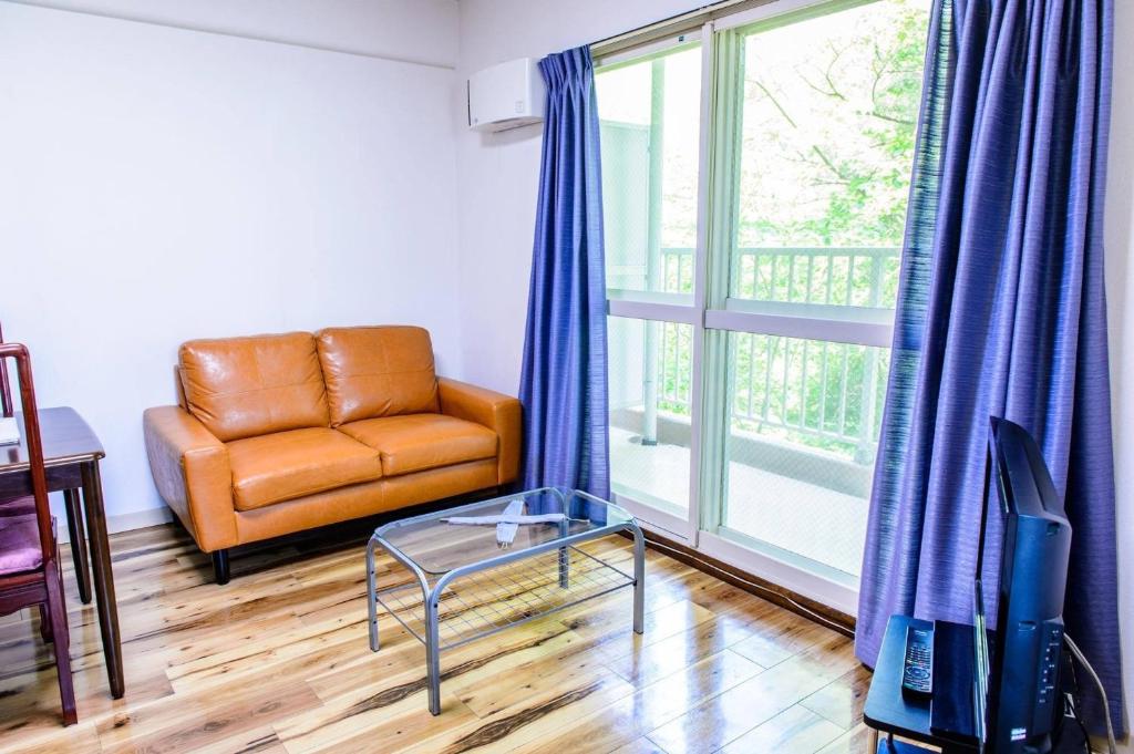 uma sala de estar com uma cadeira de couro e uma mesa de vidro em Hakuba Inn Bloom - Vacation STAY 95727 em Hakuba