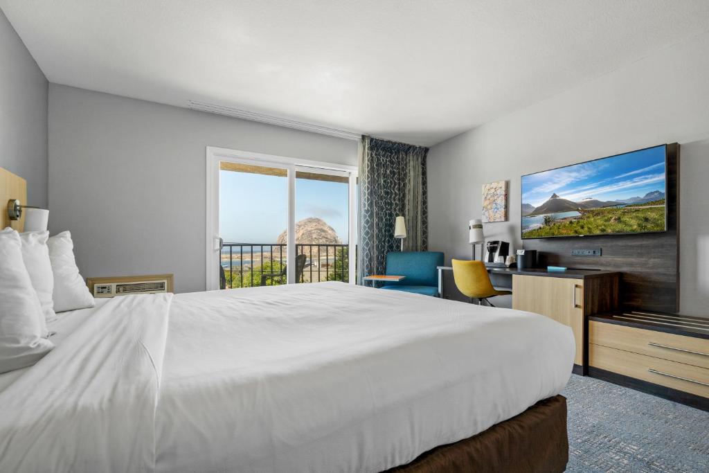 a hotel room with a large white bed and a window at Hotel Avisa Downtown in Morro Bay