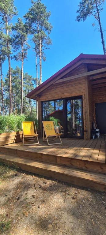 two yellow chairs on a wooden deck in front of a cabin at Schadzka w dwunastce z widokiem na jezioro in Borsk