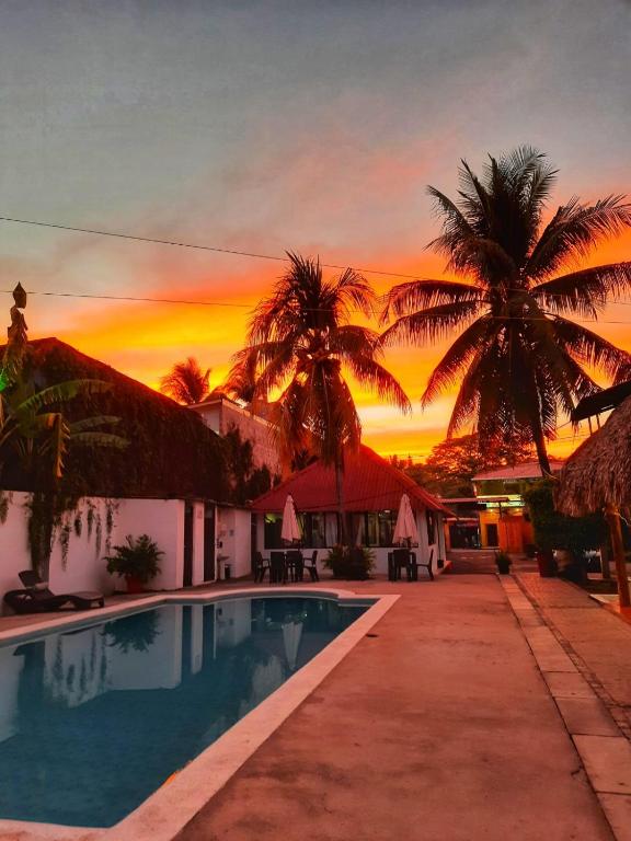 a villa with a pool and palm trees at sunset at Hotel Tunco Lodge in La Libertad