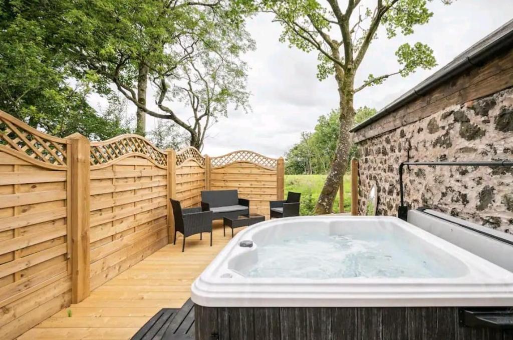 a hot tub on a deck with a wooden fence at Squirrel Cottage in Ballymena