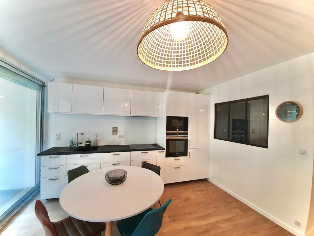 a kitchen with a table and chairs and a chandelier at Appartement résidence Le Goulvars-plage du Goviro in Quiberon