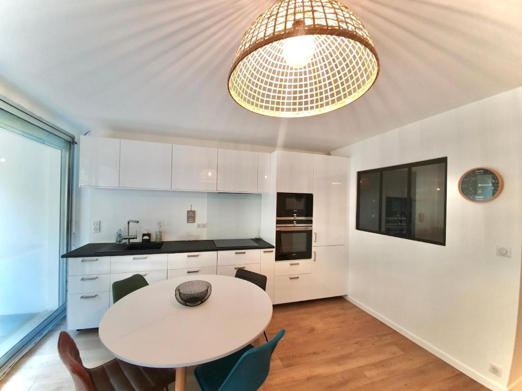 une cuisine avec une table et des chaises ainsi qu'un lustre dans l'établissement Appartement résidence Le Goulvars-plage du Goviro, à Quiberon