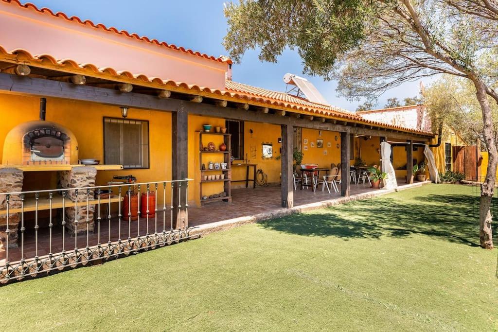 Casa amarilla con patio y patio en Casa Rural Navalonguilla con piscina en Santa Olalla del Cala