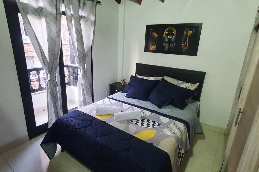 een slaapkamer met een bed met blauwe kussens en een raam bij central apartamento al lado del polideportivo sur de envigado in Envigado
