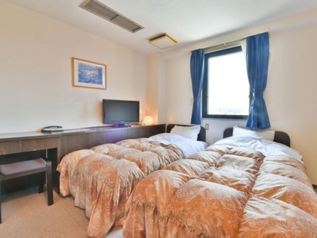 1 dormitorio con 2 camas, escritorio y TV en Suzuka Royal Hotel - Vacation STAY 38957v, en Suzuka