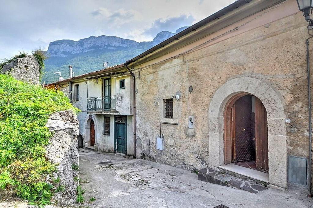 ein altes Steingebäude mit einer Tür und Bergen im Hintergrund in der Unterkunft il sentiero del riccio in Sicignano degli Alburni