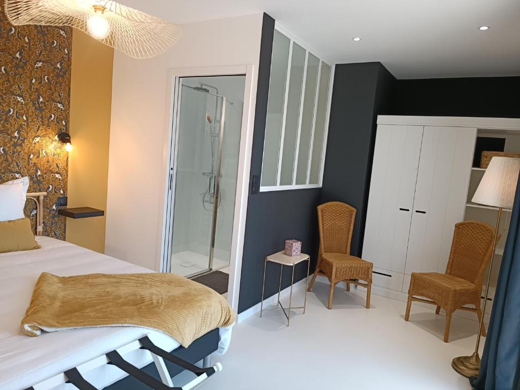 ein Schlafzimmer mit einem Bett und Stühlen sowie einer Dusche in der Unterkunft Maison Bailly in Ducey