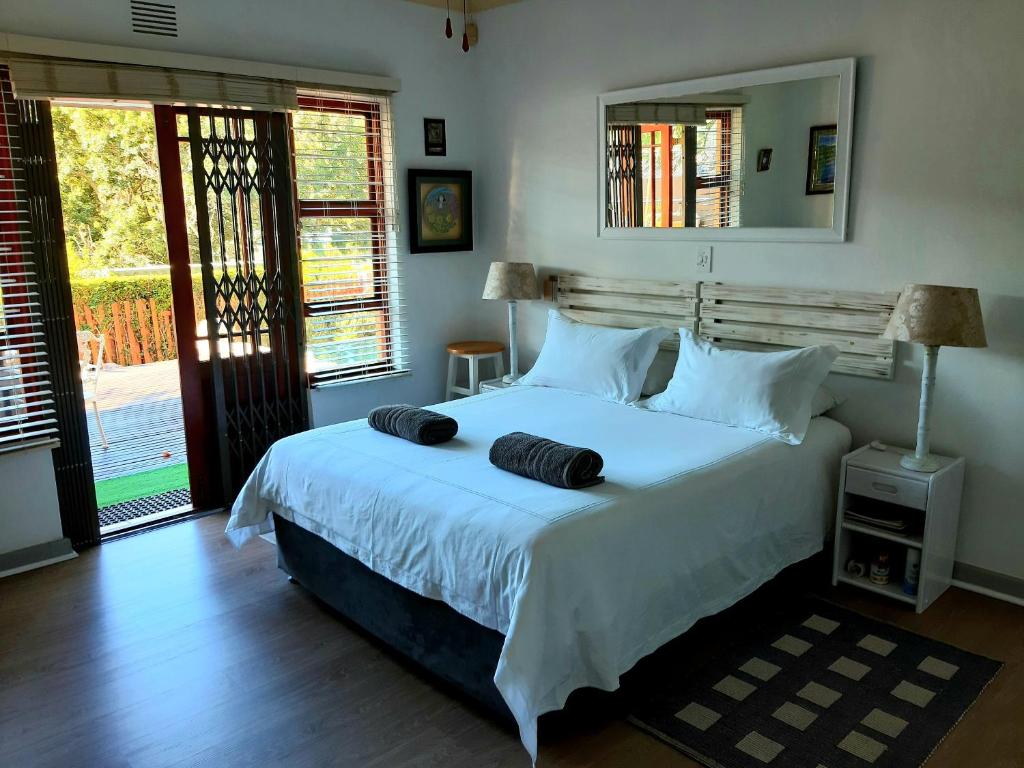 a bedroom with a large bed with two towels on it at Double Room - Robberg in Plettenberg Bay