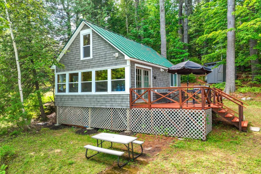 ein winziges Haus mit einer Terrasse und einem Picknicktisch in der Unterkunft Loon Cove in Waterville