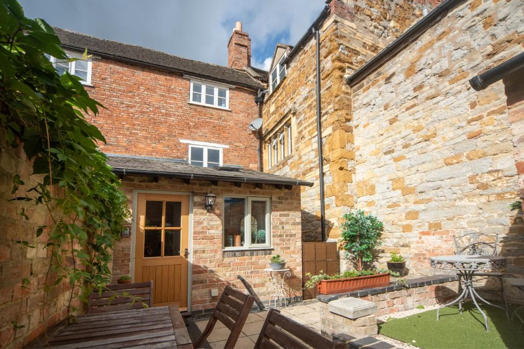 斯托爾河畔希普斯頓的住宿－Cotswolds period townhouse near Stratford-upon-Avon, central location short walk to pubs, restaurants and shops，一座带木门的老砖房的庭院