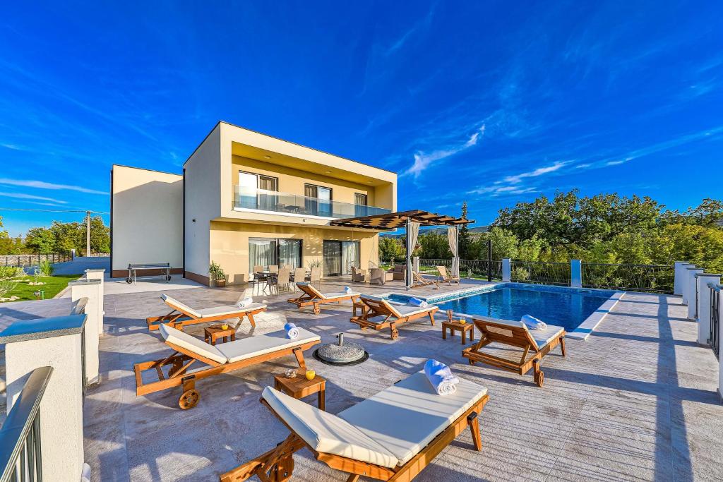 einen Hinterhof mit einem Pool und einem Haus in der Unterkunft Luxury Villa Elena in Primorski Dolac