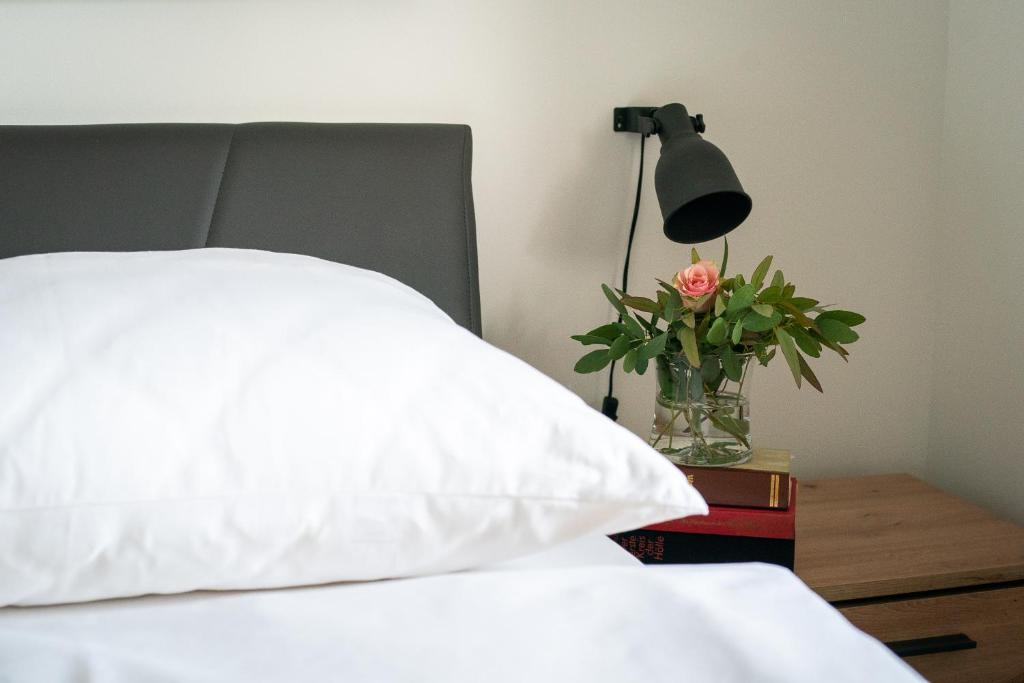 a bed with a white pillow and a vase with a flower at Ferienhaus Kaiserbaum in Illmitz